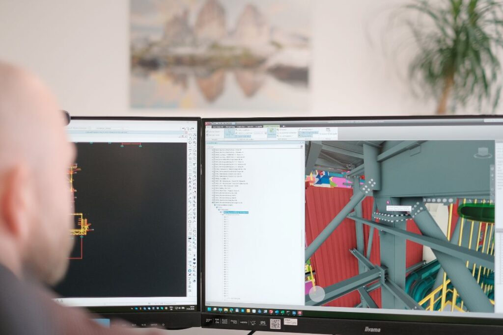 Konstrukteur arbeitet an einem 3D-Modell einer Stahlkonstruktion auf zwei Monitoren